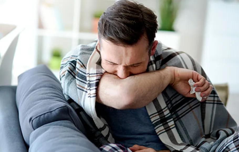 Man som hostar i armvecket