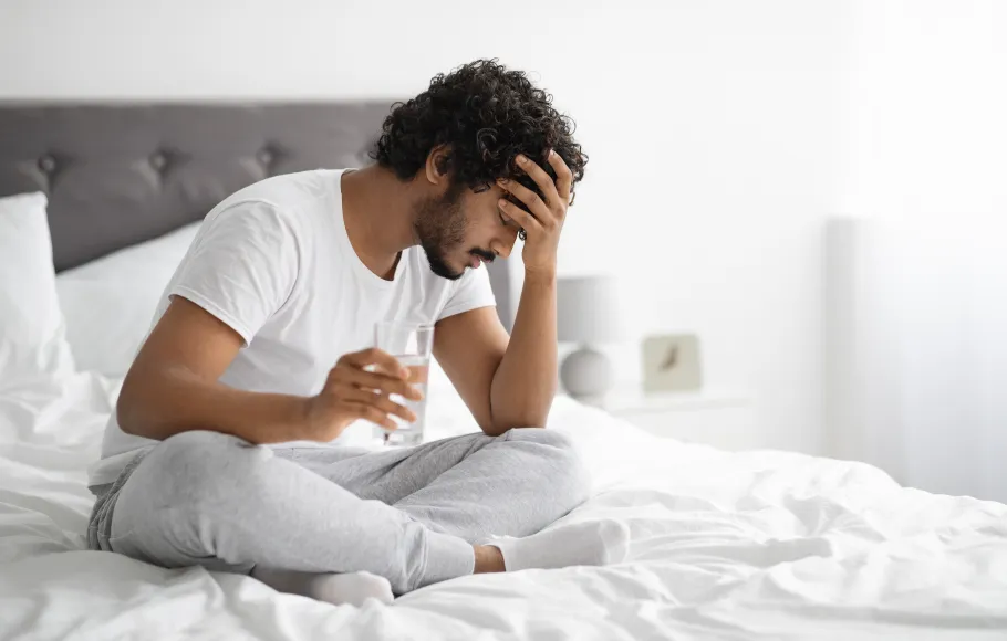 Man sitter i sängen och mår dåligt