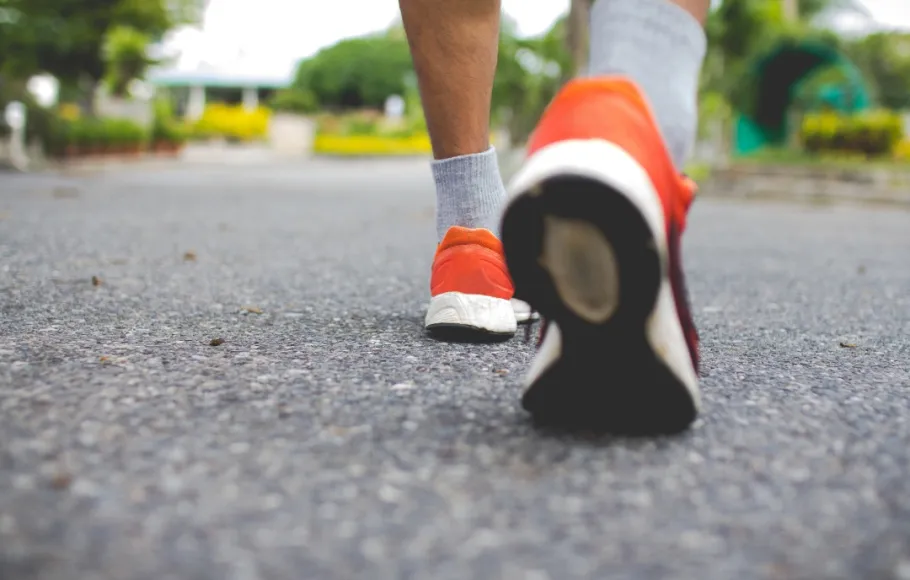 Person promenerar. Fokus på ben och skor.