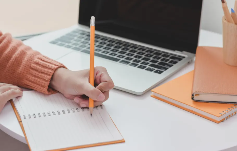 person skriver i anteckningsblock