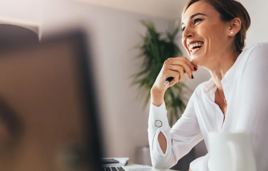 Glad kvinna vid datorn på jobbet