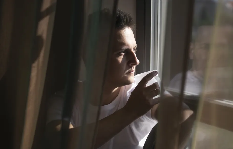 man tittar ut genom fönster