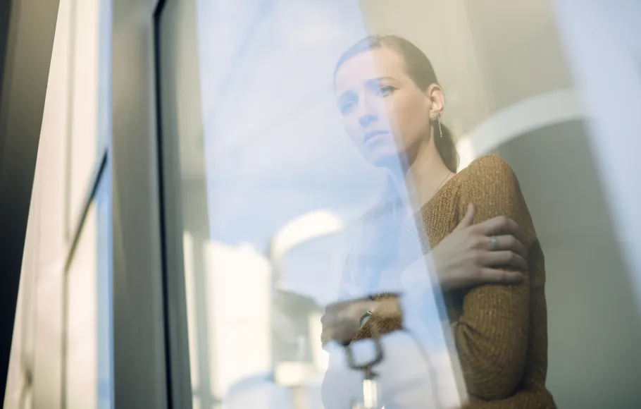 Orolig kvinna som ser ut genom ett fönster