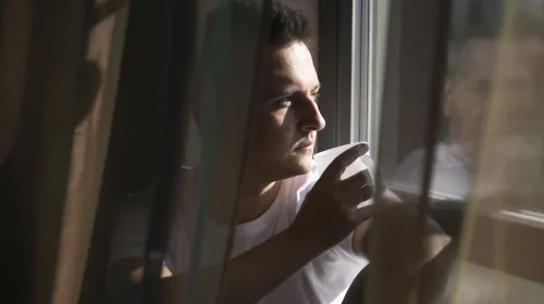 man tittar ut genom fönster